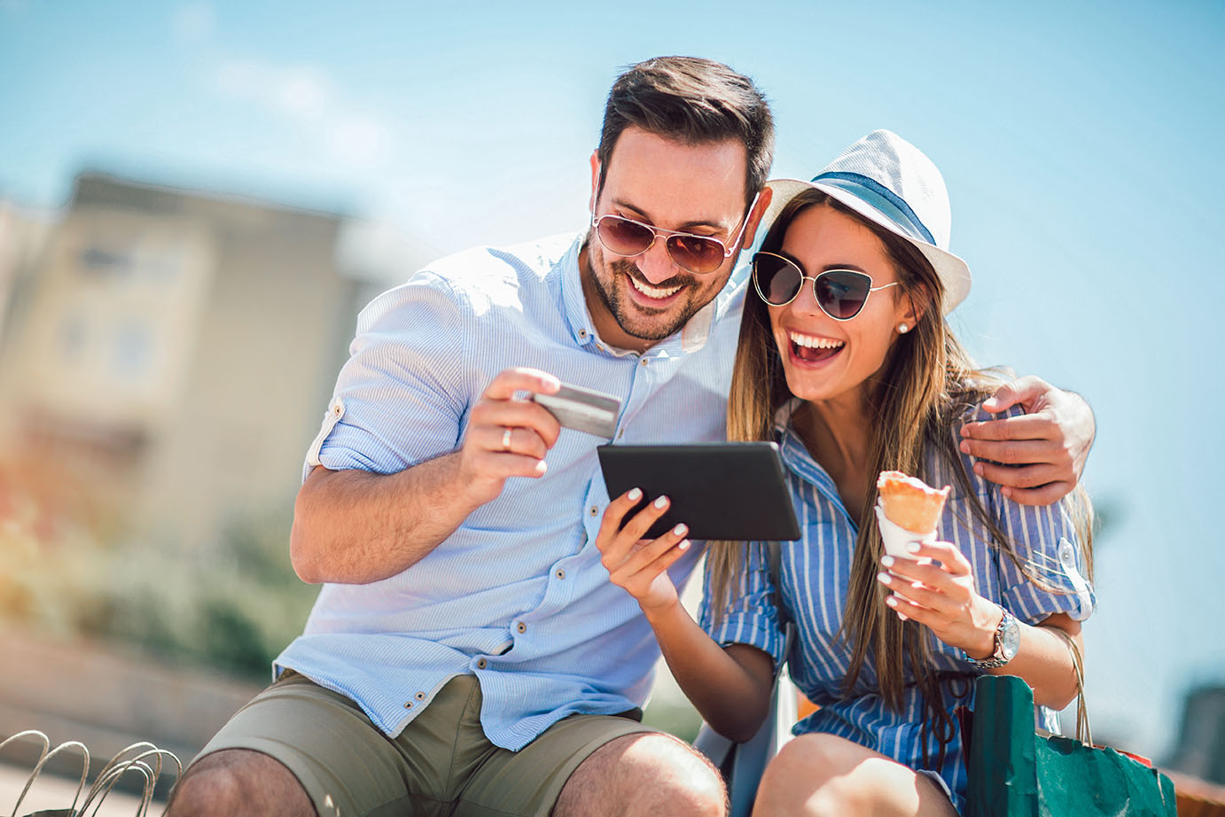 man and woman smiling at tablet with debit card in hand