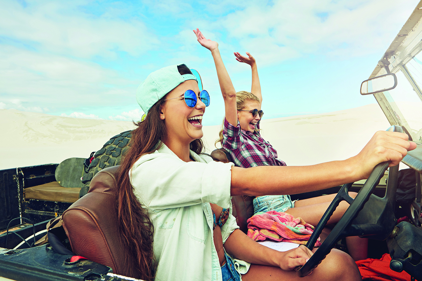 two young women smiling while driving jeep