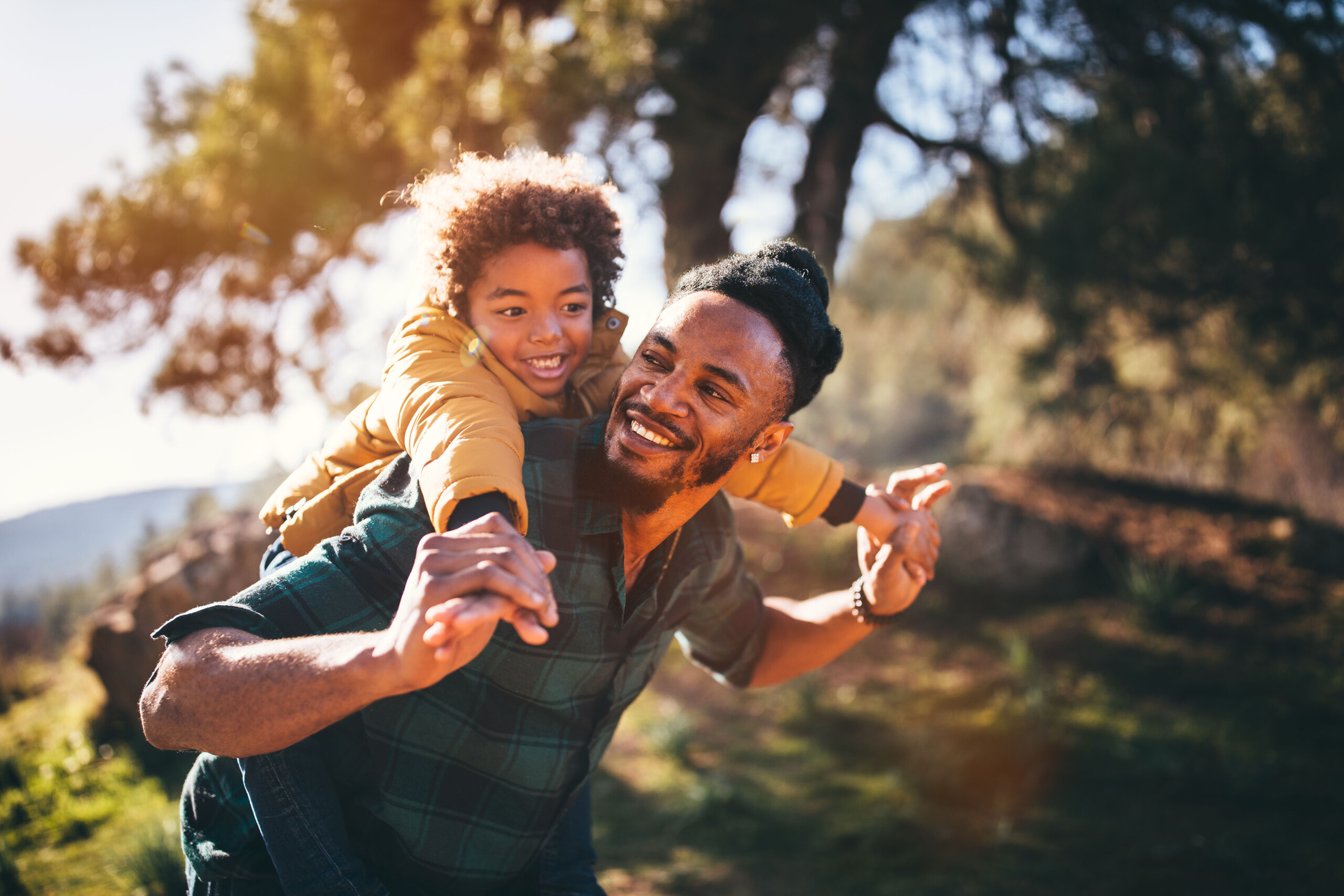 Father and son having fun with piggyback ride in nature