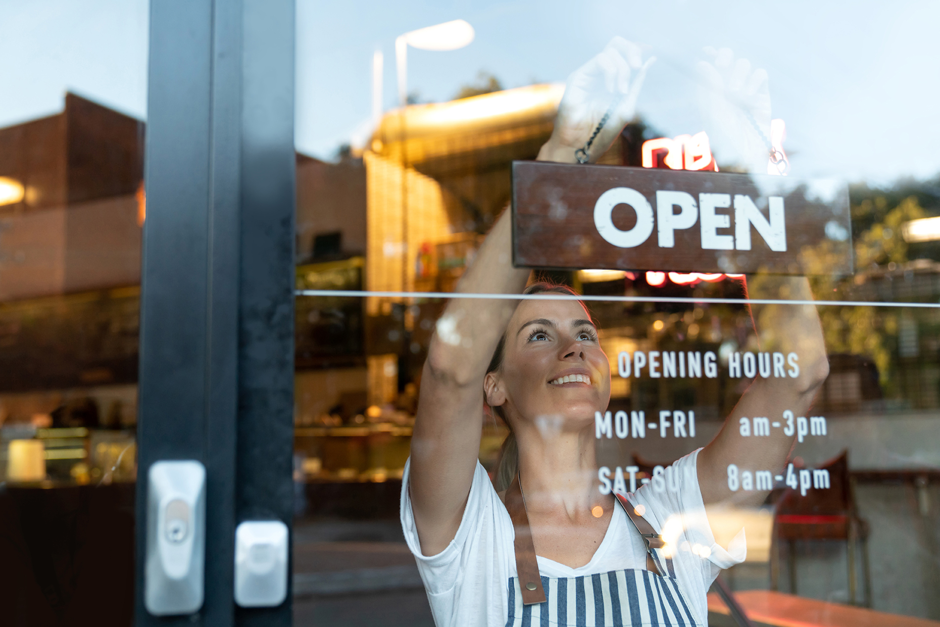 Happy business owner hanging an open sign at a cafe Preferred Partner Benefits